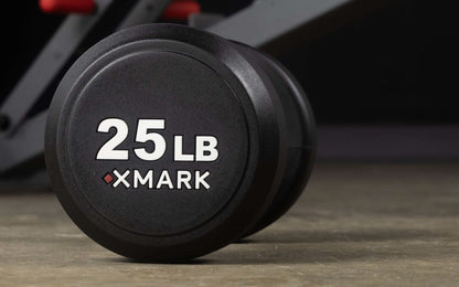 25 lb XMARK commercial urethane dumbbell on a gym floor, showcasing its quality and durability for strength training.