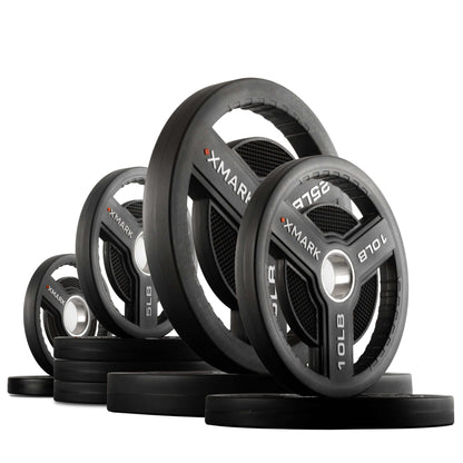 XMARK Commercial Urethane Olympic Weight Plates with tri-grip handles, showing various weights stacked for gym use.
