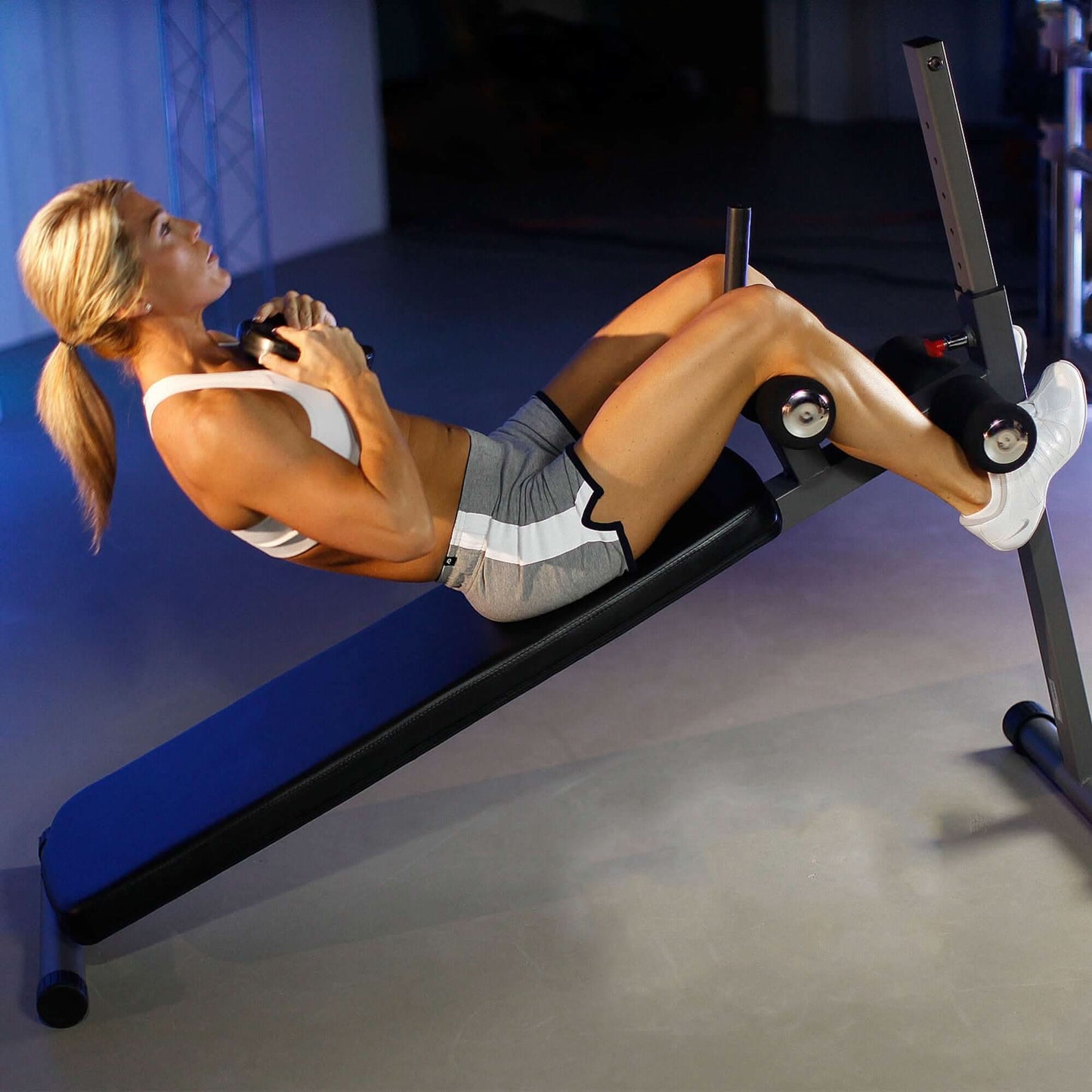 Woman performing sit-ups on an adjustable decline abdominal bench with resistance levels, showcasing ergonomic design and stability.