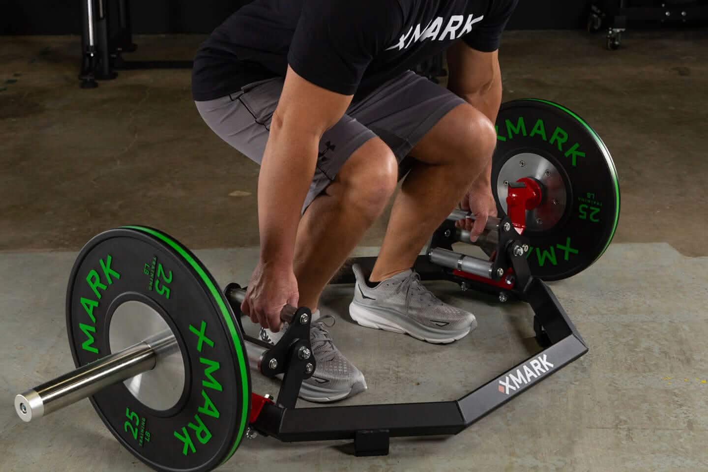 Person lifting the Olympic Hex Trap Bar with knurled handles and green weight plates for strength training.