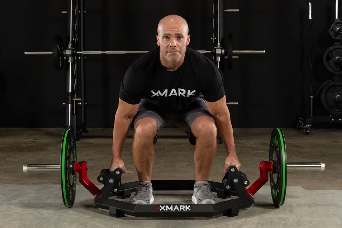 Man performing deadlifts with XMark Olympic Hex Trap / Shrug Barbell, showcasing its knurled grips and elevated sleeves.
