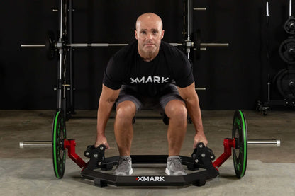 Man performing deadlifts with XMark Olympic Hex Trap / Shrug Barbell, showcasing its knurled grips and elevated sleeves.