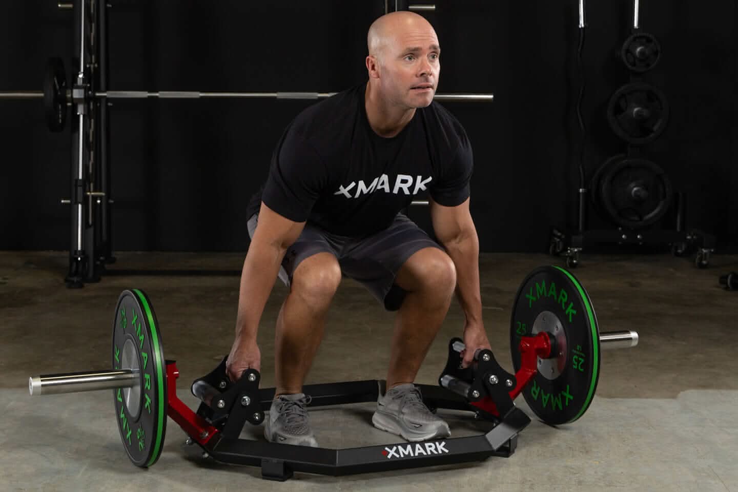 Man using XMARK Olympic hex trap barbell for deadlifts, showcasing tri-grip handles and weight plates.