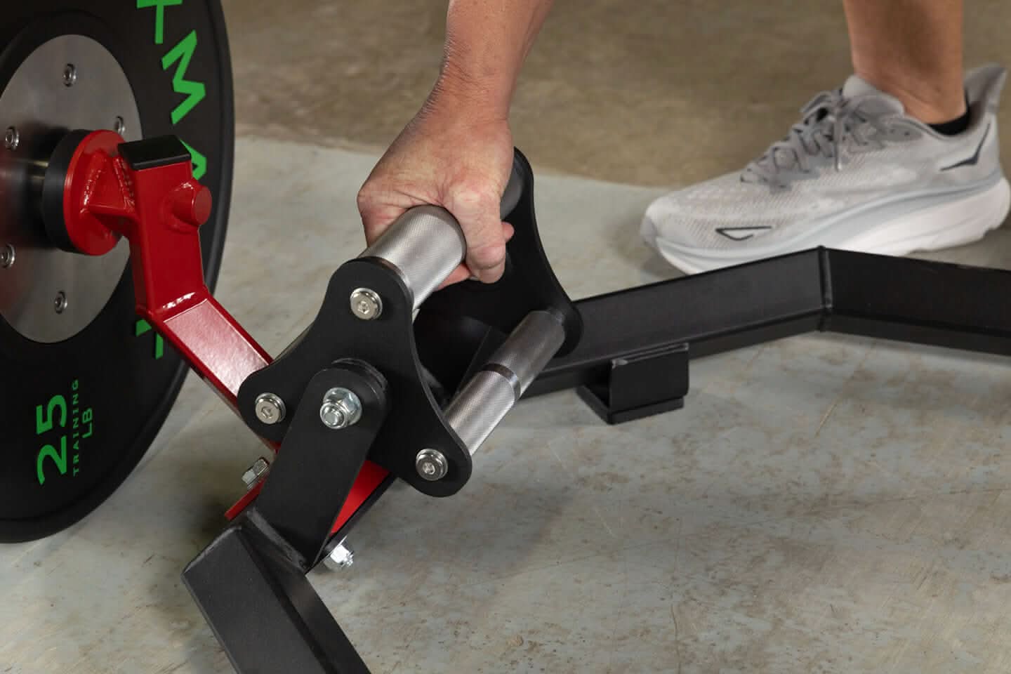 Close-up of a hand gripping the revolving tri-grip handle on an Olympic hex trap barbell with weight plates attached.