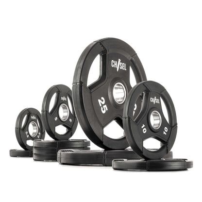 Chisel Olympic weight plates in varying sizes arranged on a flat surface, featuring recessed handles and rubber encasement.