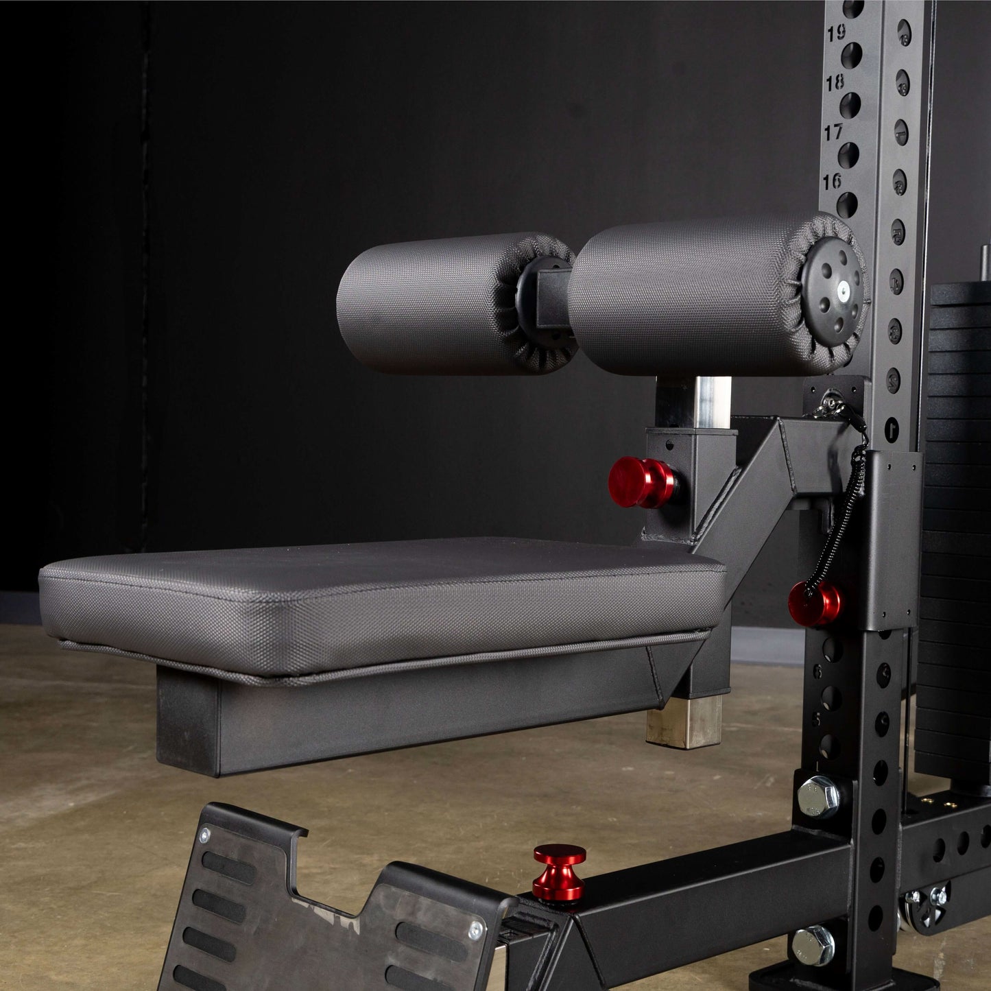 Close-up of a lat pulldown seat attachment with foam padding and adjustable roller pads on a functional trainer.