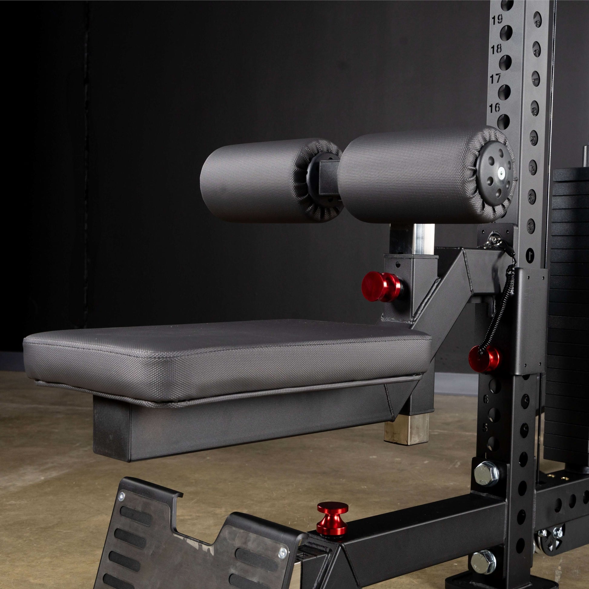 Close-up of a lat pulldown seat attachment with foam padding and adjustable roller pads on a functional trainer.