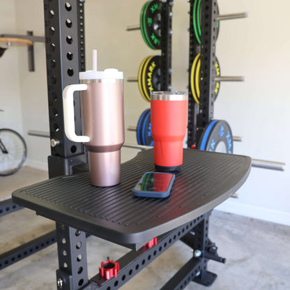 Close-up of two insulated tumblers and a smartphone on a sturdy step attachment for a power rack.